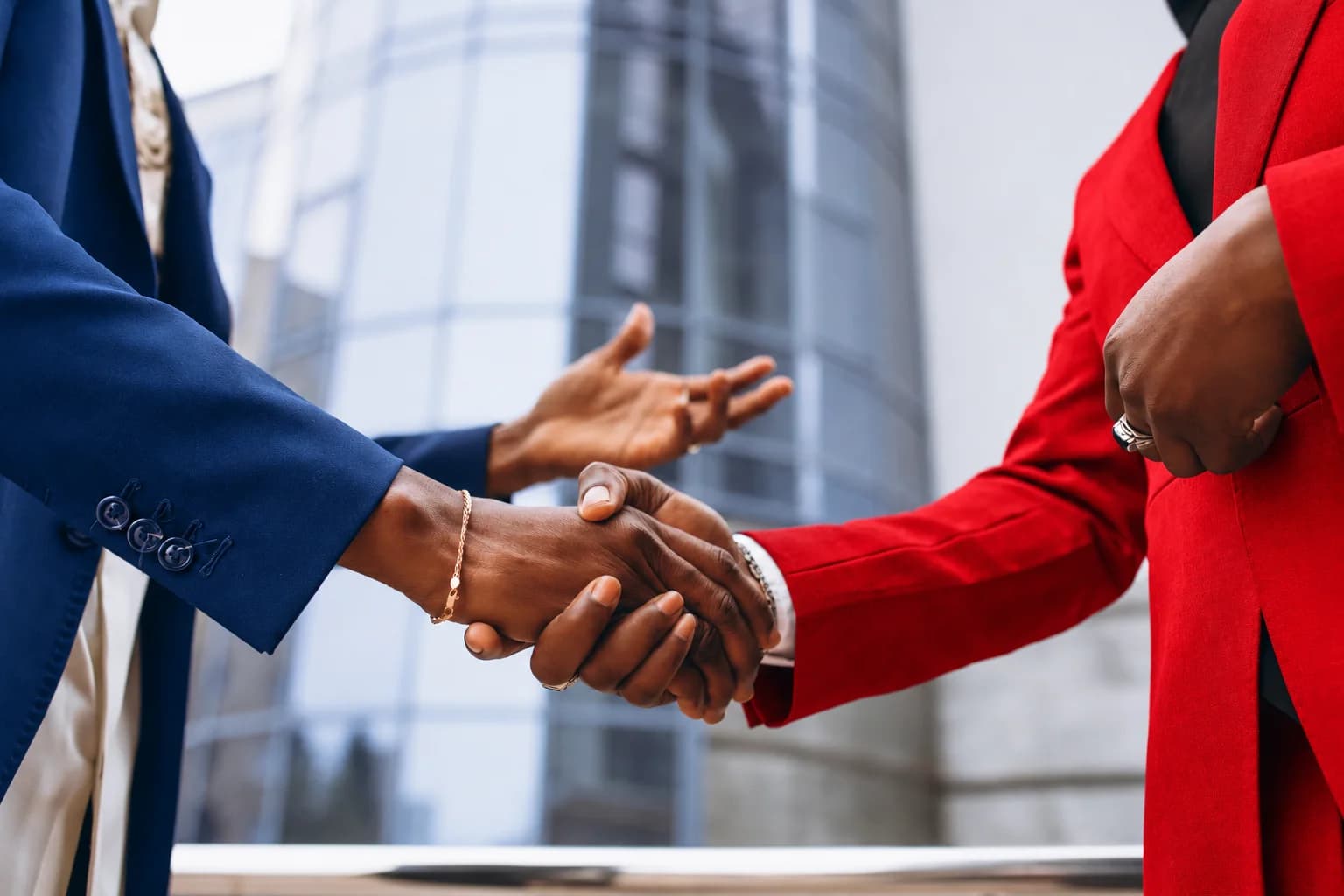 Business professionals in blue and red suits shaking hands