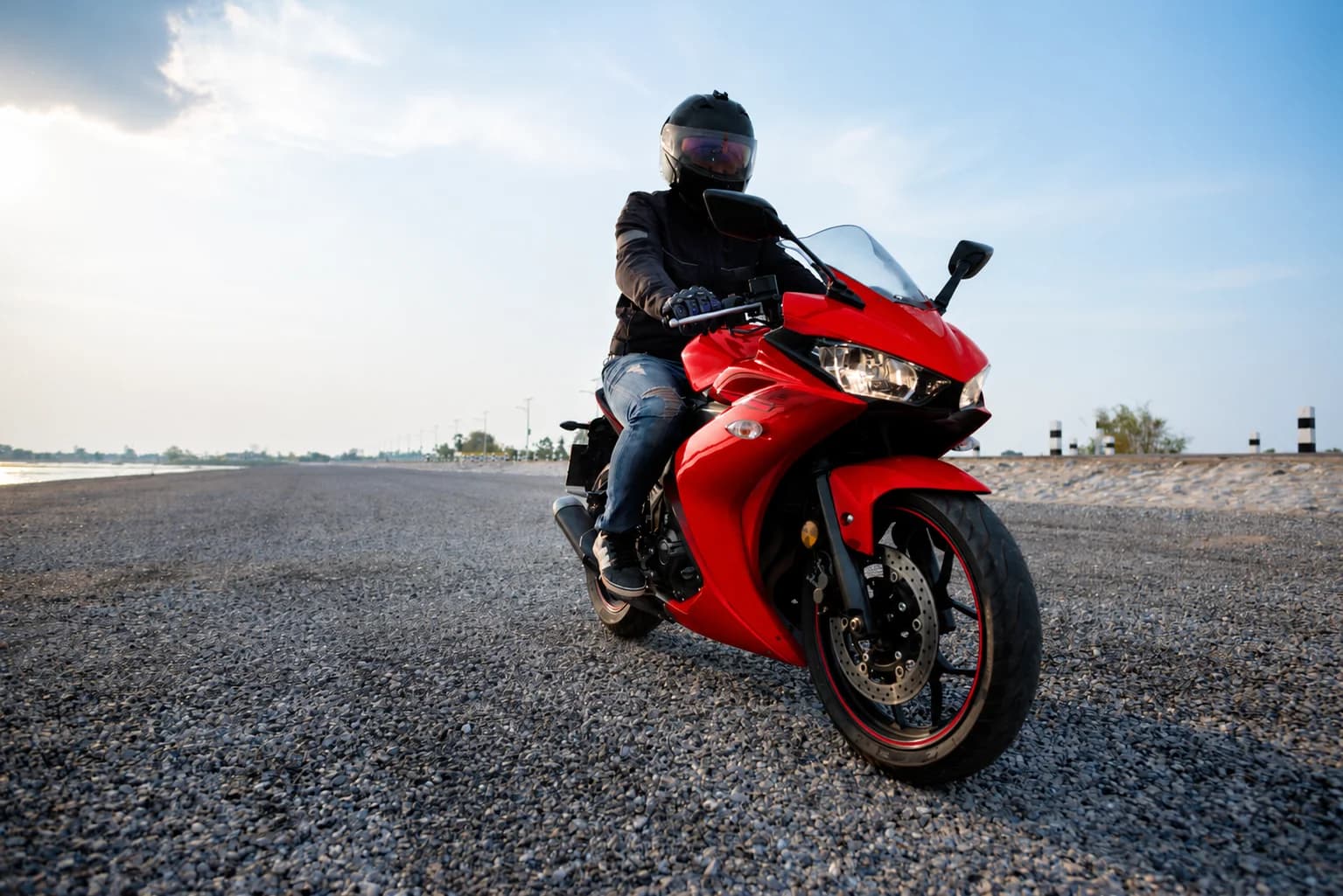 Helmeted rider on a red motorcycle on an open road